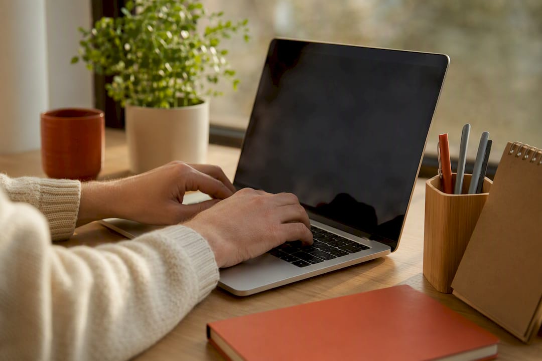 Mani che digitano sulla tastiera di un laptop alla scrivania dell'ufficio
